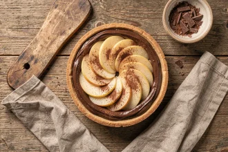 Tarte poire chocolat vue de dessus sur table en bois avec napkin lin et copeaux de chocolat